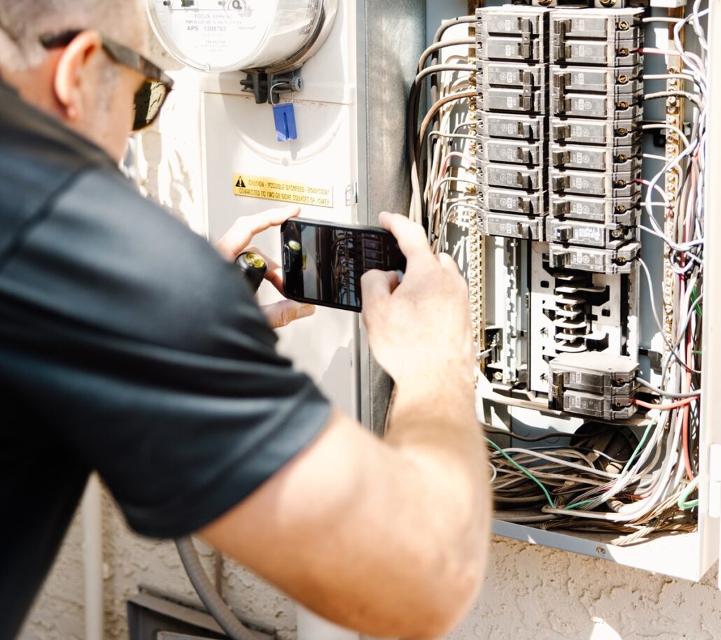 Home inspector checking electrical panel during thorough property inspection in Phoenix, AZ.