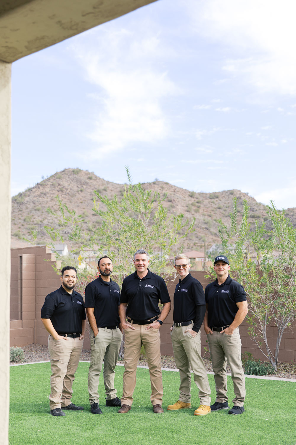 Home inspection team standing outdoors in residential yard in Arizona for company group photo.
